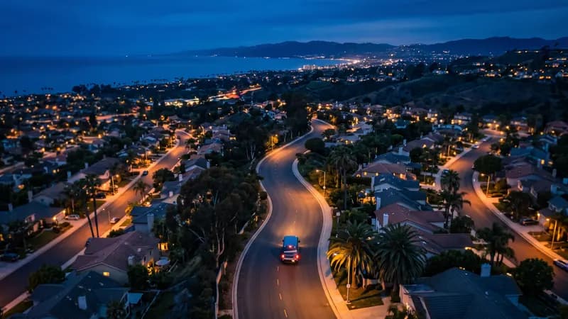 A service van parked on a quiet suburban street at blue hour, streetlights on, houses softly lit, navy and cobalt grade, no logos