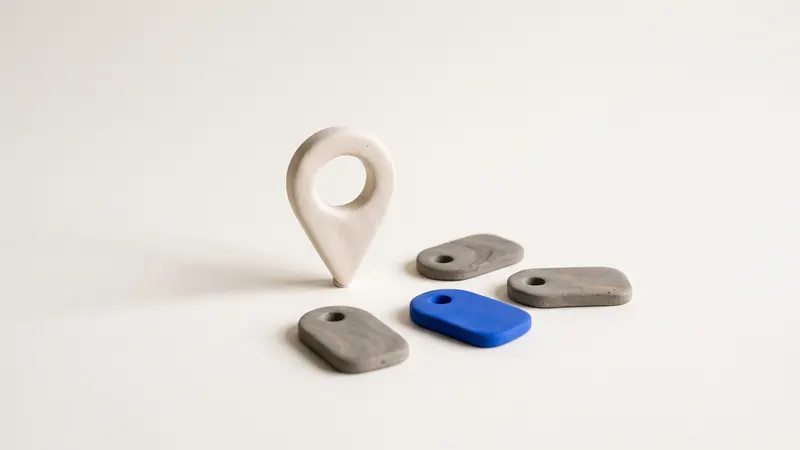 A matte clay map pin with a cobalt top beside small clay tag shapes, on a warm off-white background