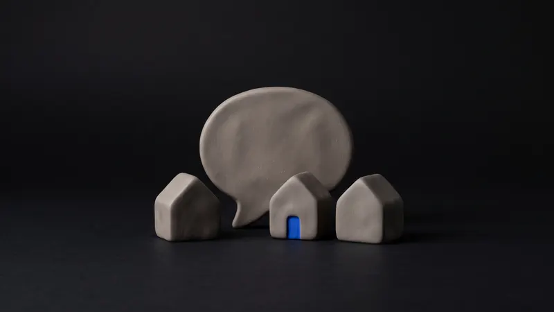 A matte clay magnifying glass resting over a small clay map pin with a cobalt tip, on a near-black background